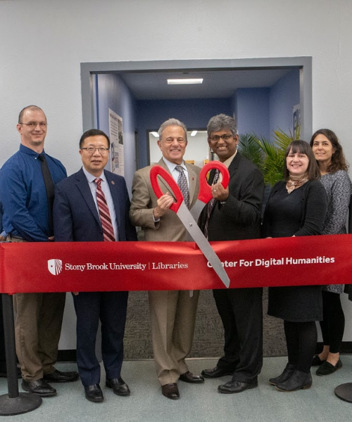 Administrators and librarians holding the big scissor before cutting ribbon